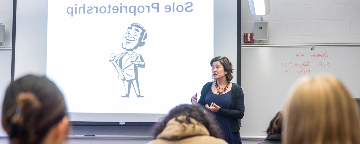 SPU的一位商学教授在SPU的教室前面对她的学生讲话.