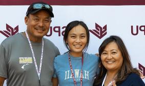 A Seattle Pacific University family including mother, daughter and father in front of an SPU banner.